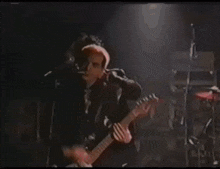 a man with red hair is playing a guitar on stage in a dark room .