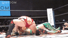 two women are wrestling in a ring with a sign that says softbank in the background