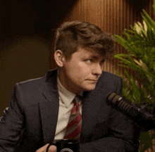 a man in a suit and tie is sitting in front of a microphone and holding a mug that says ' washington '