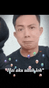 a man in a black shirt is surrounded by balloons and the words hai aku ultah loh