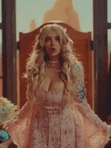 a woman in a pink lace dress is standing in front of a window