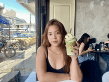 a woman is holding a cup of green tea