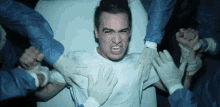 a man is laying in a hospital bed surrounded by nurses and doctors .