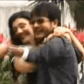 a man and a woman are hugging each other while standing next to each other .