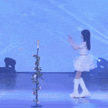two girls in white dresses are dancing on a stage with flowers in the background