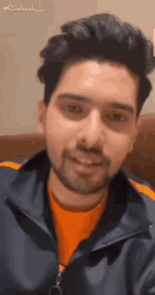 a man with a beard is smiling and wearing an orange shirt .