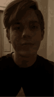 a young man taking a selfie in a dark room with his eyes closed