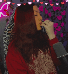 a woman singing into a microphone with hearts on the wall behind her that say i love you