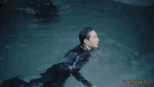 a man in a wet suit is swimming in a pool with judleklek702 written in the corner