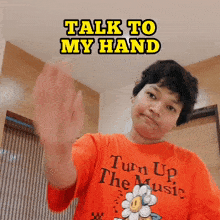 a man wearing an orange shirt that says turn up the music waves his hand