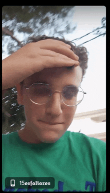 a young man wearing glasses and a green shirt with 15osfaliaro written on the bottom