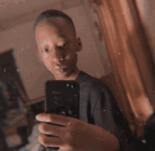 a young boy is taking a selfie with his phone in front of a mirror