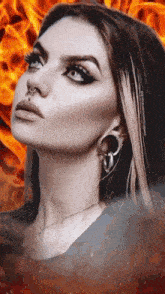 a close up of a woman 's face with a flame in the background