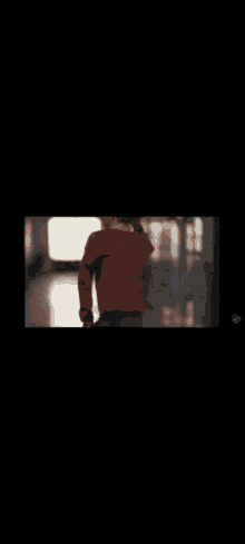 a person wearing a red sweater is walking down a hallway .