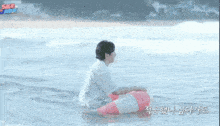 a man in a white shirt is holding a red and white life preserver in the ocean