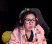 a girl with glasses and headphones is sitting in a chair .