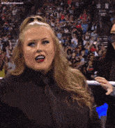 a woman in a black shirt and tie stands in front of a crowd with the letters n on the bottom