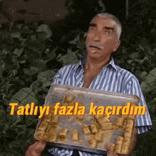 a man in a striped shirt is holding a tray of food with a foreign language written on it .