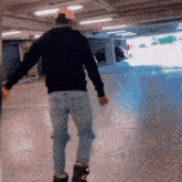 a man wearing a black sweatshirt and jeans is walking in a parking garage