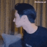 a man in a black shirt is sitting on a couch looking at something .
