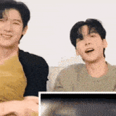a couple of young men are sitting next to each other on a couch .