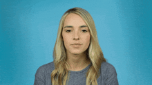 a woman with blonde hair is wearing a grey sweater