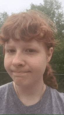 a young woman with red hair is wearing a grey shirt