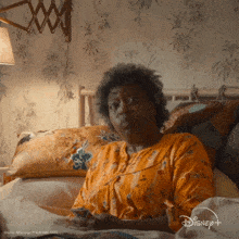 a woman is laying in a bed with a disney logo on the bottom right