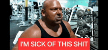 a man sitting in a gym with a sign that says i 'm sick of this shit