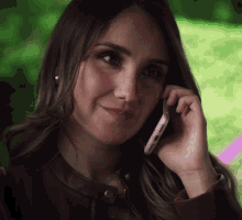 a woman in a leather jacket is talking on her cell phone