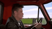 a man is driving a red truck and looking out the window