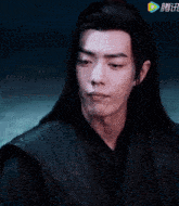 a man with long black hair is wearing a black jacket with a yellow arrow pointing to the right