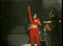 a woman in red pants is singing into a microphone on a stage .