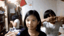 two girls are making a heart shape with their hands in front of a picture of a flamingo