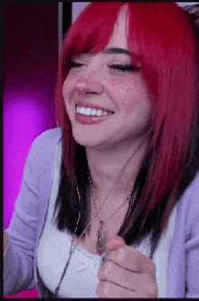a woman with red hair and freckles is wearing a necklace and smiling .