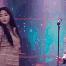 a woman is singing into a microphone while a man holds a guitar