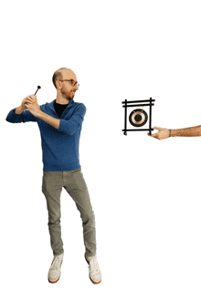 a man in a blue sweater is holding a dart and a hand is holding a target