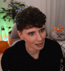 a young man is sitting in a chair and making a funny face in front of a christmas tree .