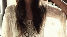 a woman is wearing a white lace top and a bracelet on her wrist