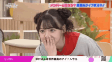 a girl covering her mouth with her hands in front of a screen that says ' リリリリ ' on it