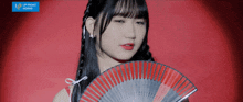 a girl is holding a fan in front of a red background that says upfront works on it