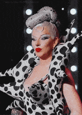 a woman wearing a black and white polka dot dress and a silver hat