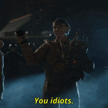 a man in a monster costume is holding a phone and says you idiots in yellow letters