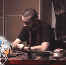 a man with a beard is sitting at a table with cards and a bottle
