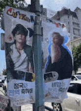 two posters on a pole with one that says jungkook on it