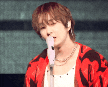 a man singing into a microphone wearing a red jacket