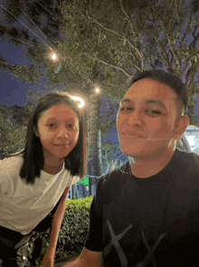 a man and a girl are posing for a picture and the man is wearing a black shirt with the letters xx on it