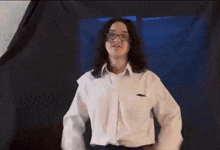 a woman wearing glasses and a white shirt is dancing