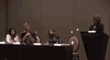 a group of people are sitting at a table with microphones and a podium that says omni hotels