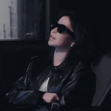 a woman wearing black sunglasses and a leather jacket